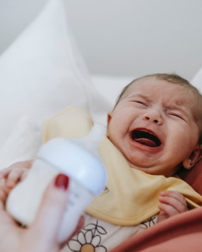 bebe chorando e mão tentando ajudar