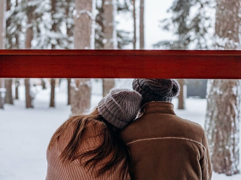 mulher com a cabeça no ombro de seu homem olhando a neve
