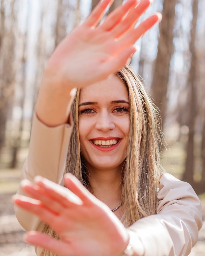 mulher sorrindo com as mãos na frente do rosto