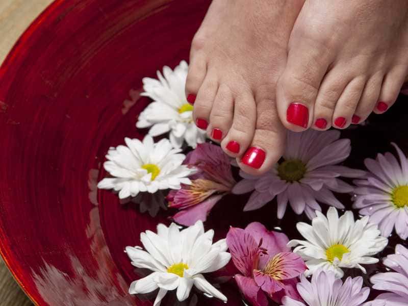 mulher colocando os pés dentro de uma basia com flores