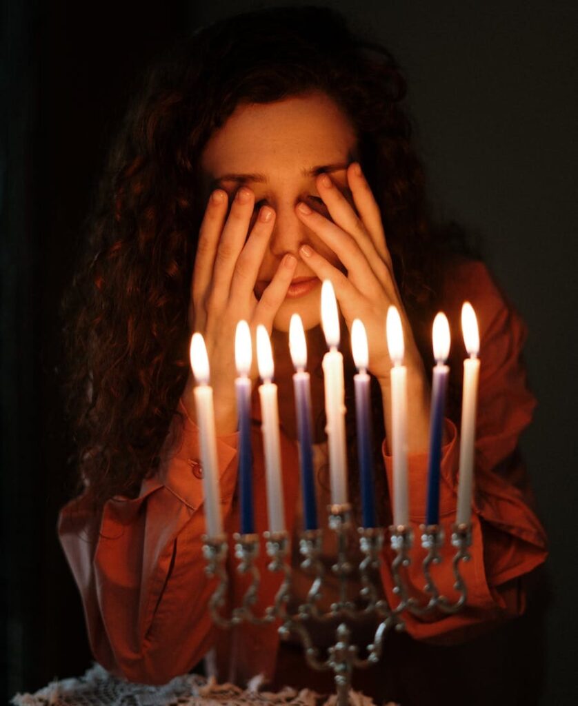 Mulher rezando na frente de muitas velas